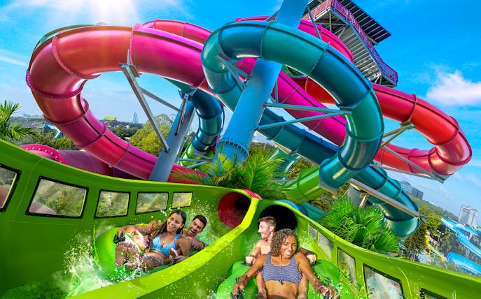Visitors enjoying a water slide at Aquatica Orlando with colorful tubes in the background.