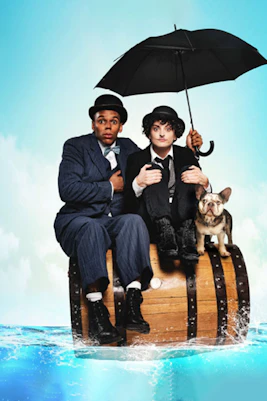Charlie & Stan performers sitting on a barrel with a dog, holding an umbrella.