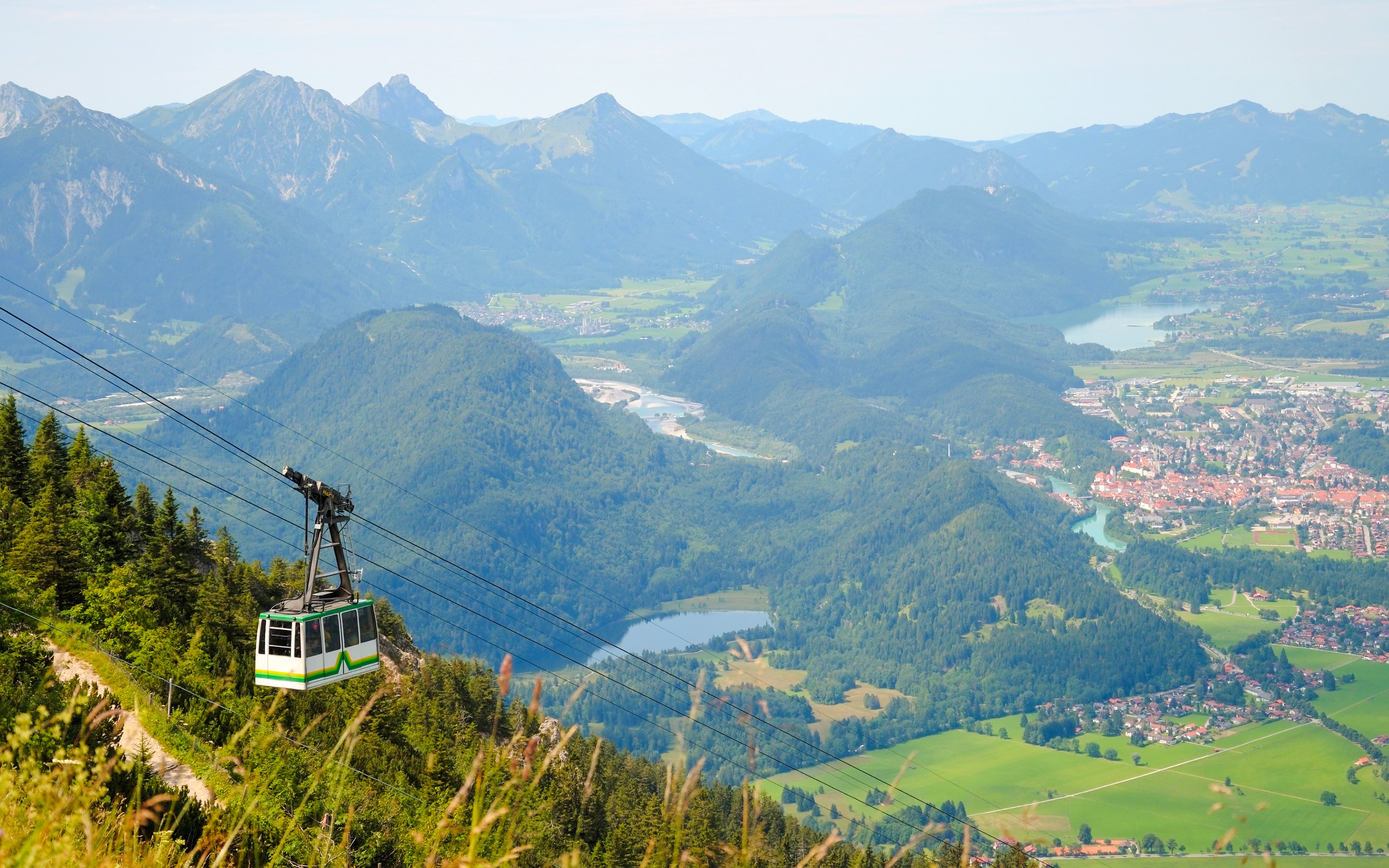 Tegelberg Cable Car ascending over lush green mountains in Bavaria, Germany.