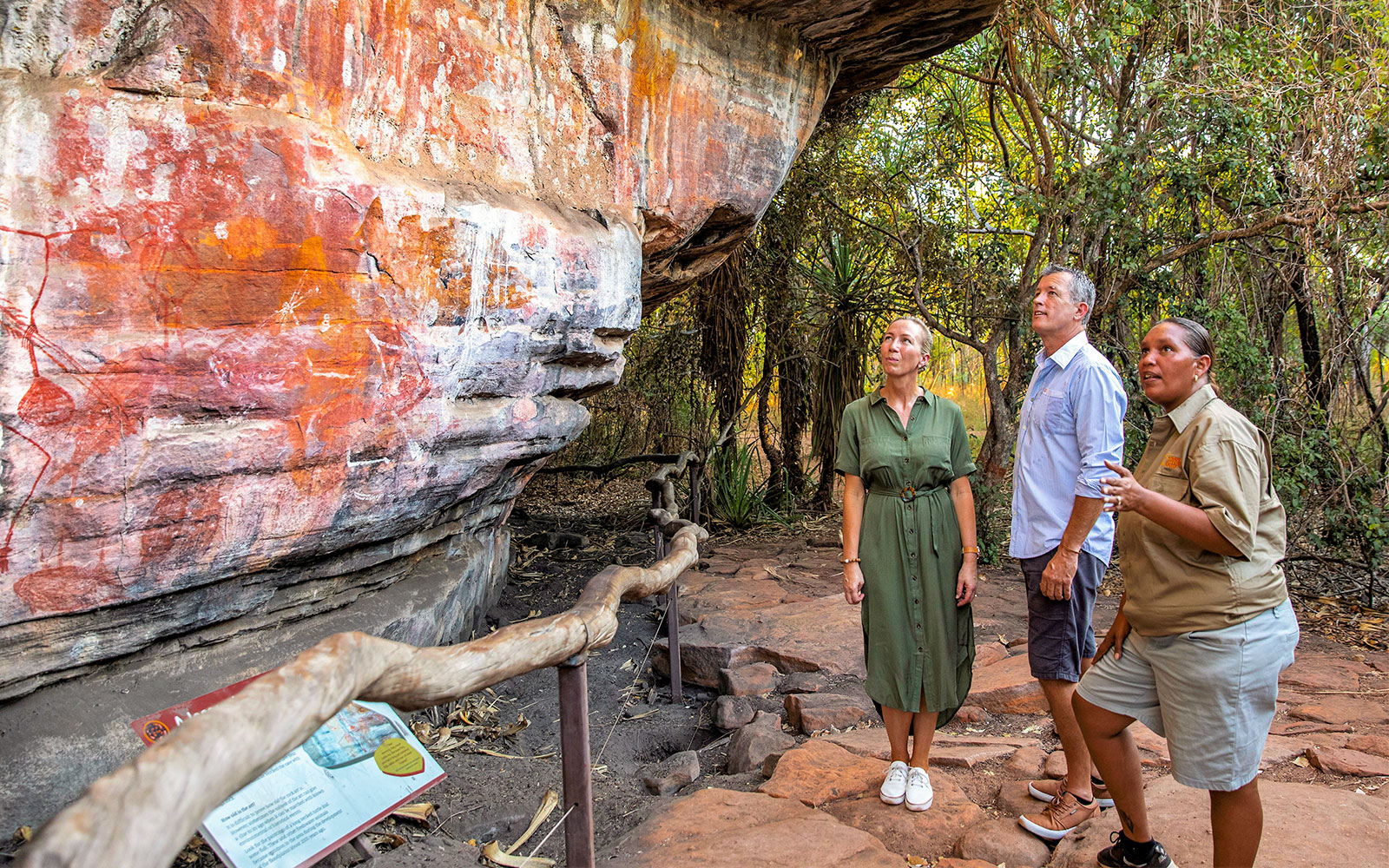 Visitors observing ancient Aboriginal rock art in Kakadu National Park during a guided tour.