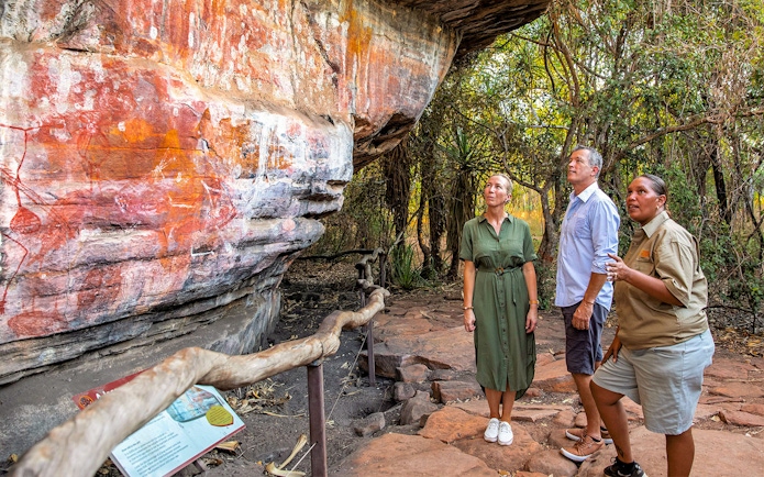 Visitors observing ancient Aboriginal rock art in Kakadu National Park during a guided tour.