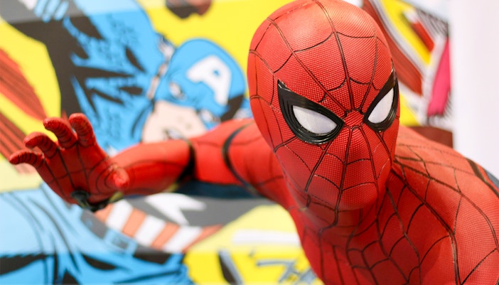 Spider-Man figurine in action pose with comic book background.