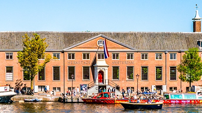 H'ART Museum exterior with canal view in Amsterdam, featuring boats and historic architecture.