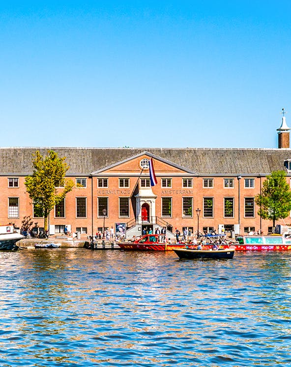 H'ART Museum exterior with canal view in Amsterdam, featuring boats and historic architecture.