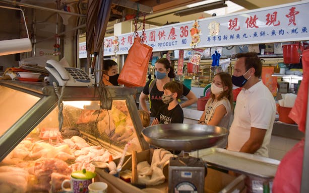 Market tour group observing meat display at a local vendor.