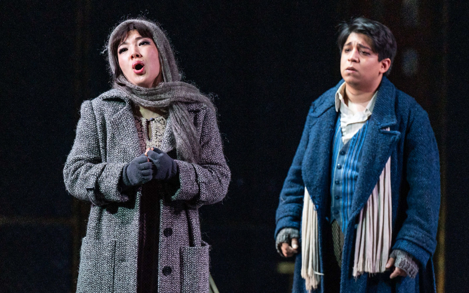 Opera performers in a scene from La Bohème, wearing period costumes on stage.