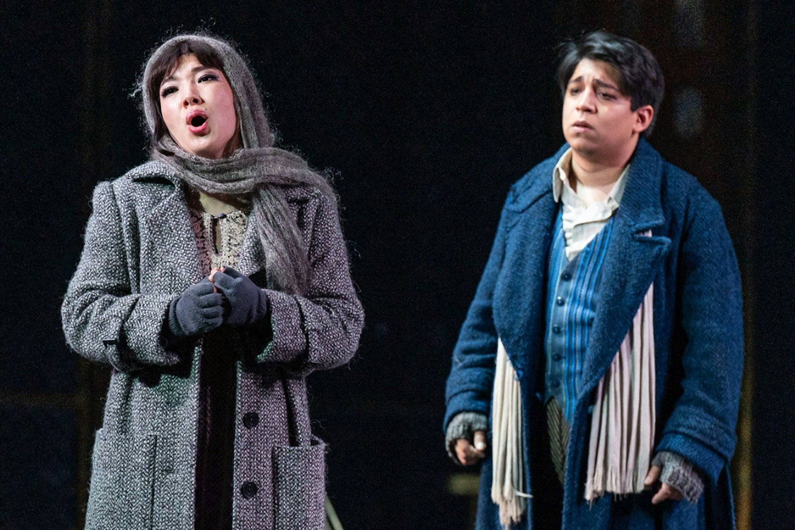 Opera performers in a scene from La Bohème, wearing period costumes on stage.