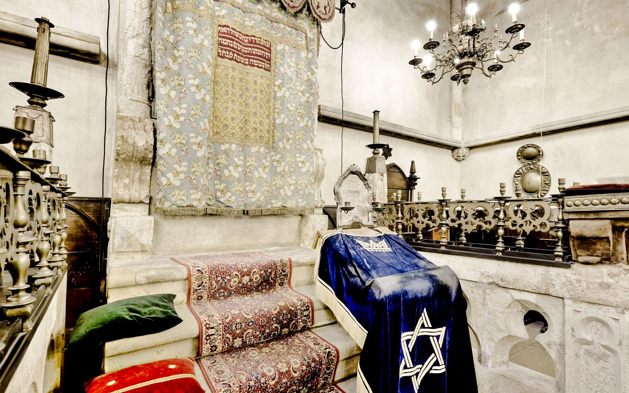 Old-New Synagogue interior with ornate Torah ark and chandeliers in Prague Jewish Quarter.