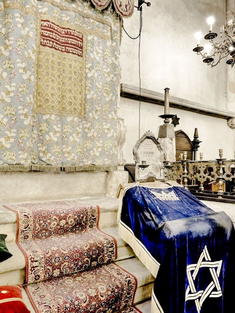 Old-New Synagogue interior with ornate Torah ark and chandeliers in Prague Jewish Quarter.