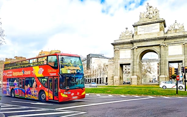Red double-decker bus on Madrid sightseeing tour near Puerta de Alcalá.