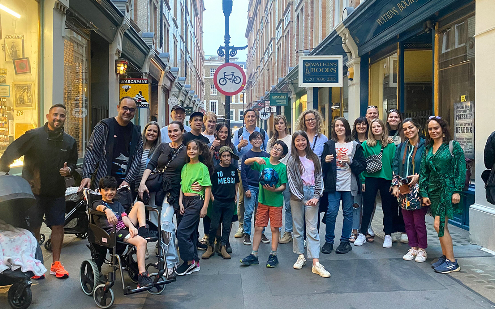 Group of people gathered in a narrow street with shops in the background.