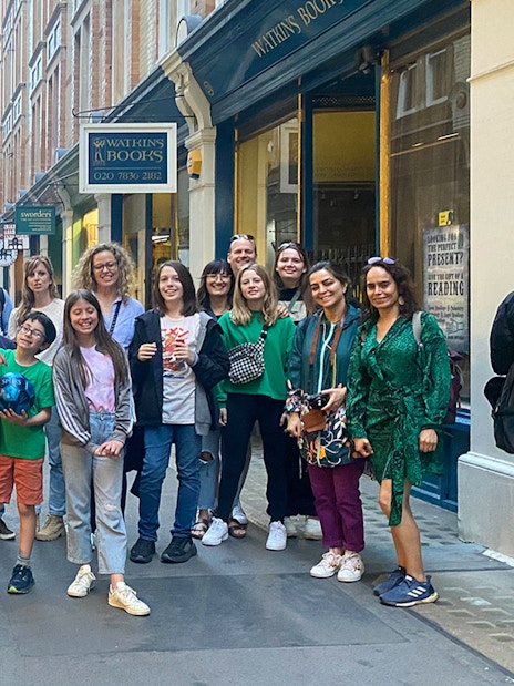 Group of people gathered in a narrow street with shops in the background.