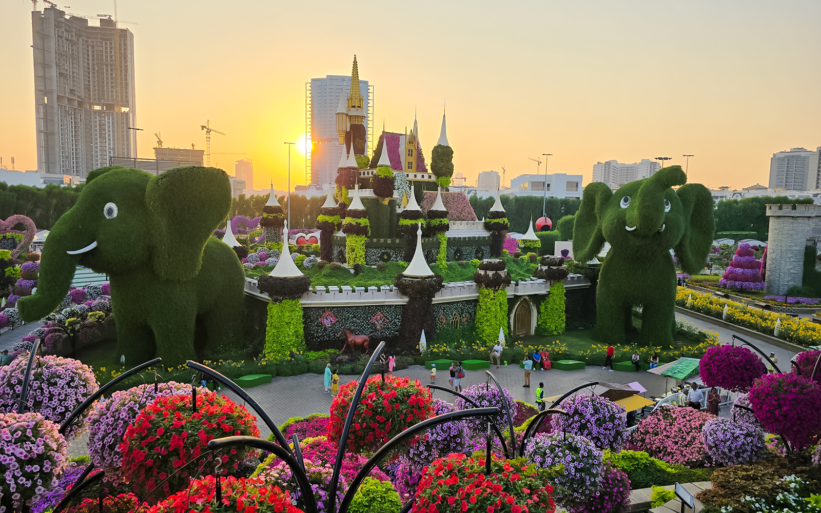 Dubai Miracle Garden with floral castle and elephant topiaries at sunset.