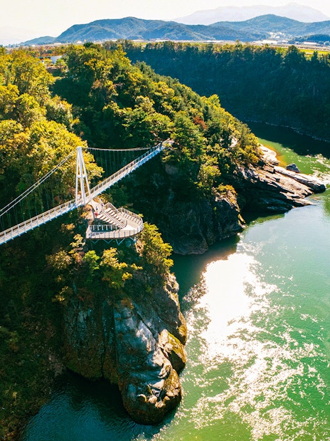 Suspension bridge over lush valley and river on DMZ 2nd Tunnel & Cliffside Path tour.