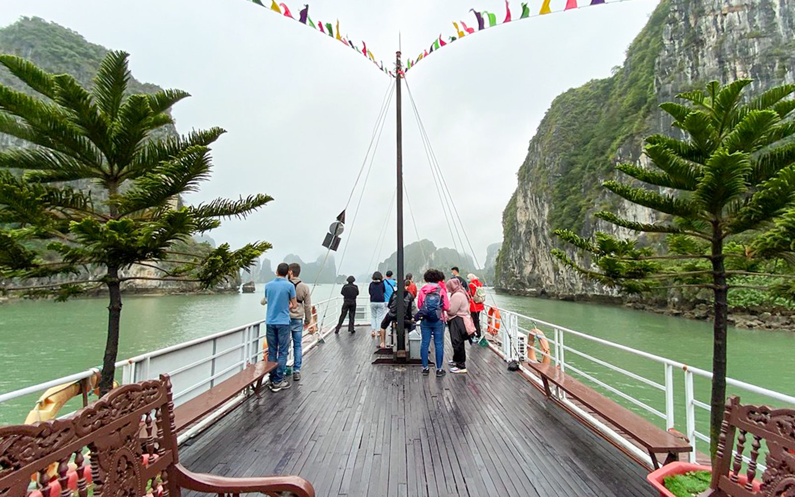 People on the Dragonfly Standard Cruise deck, surrounded by limestone cliffs in Halong Bay.