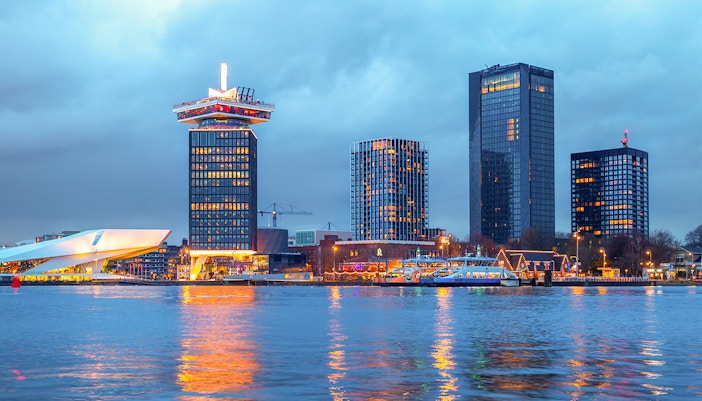 Amsterdam Noord skyline with A'DAM Tower and Eye Film Museum at dusk.
