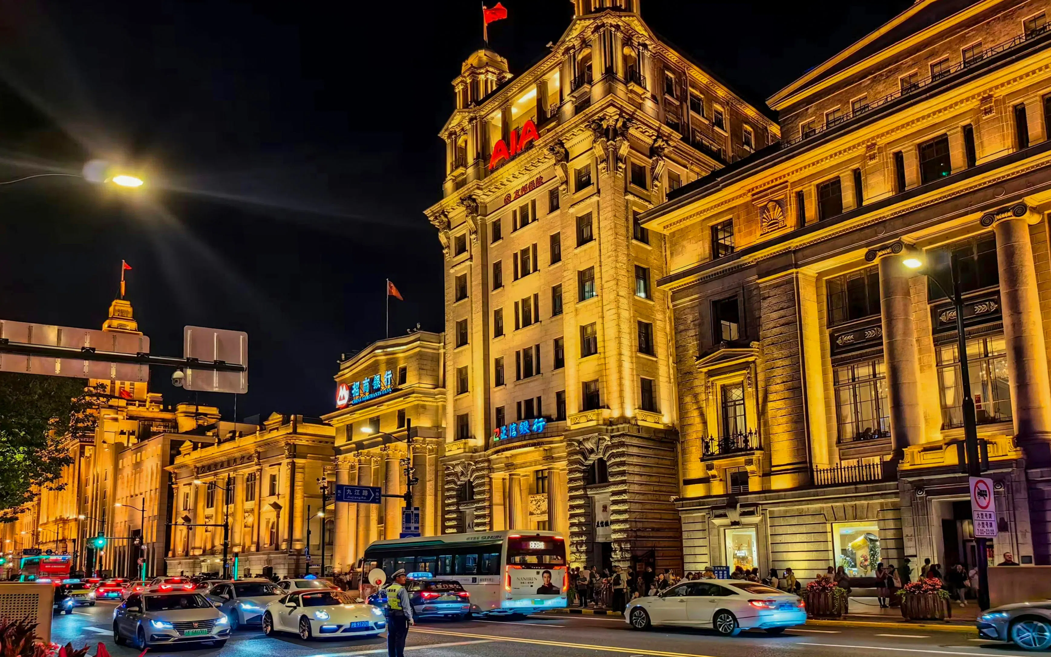 Night view of illuminated historic buildings along the Bund in Shanghai, China, with traffic on the street.