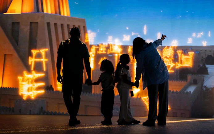 Family exploring illuminated ancient structures at London Timewalk Exhibition.