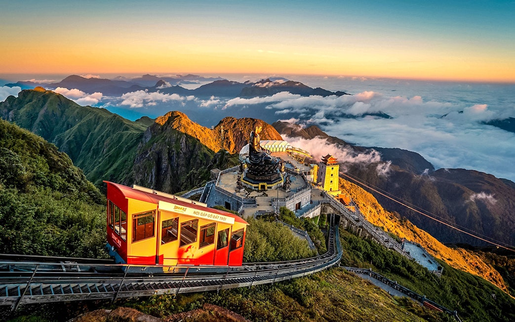 Cable car ascending Fansipan Mountain with temple and statue at Sun World Fansipan Legend, Vietnam.
