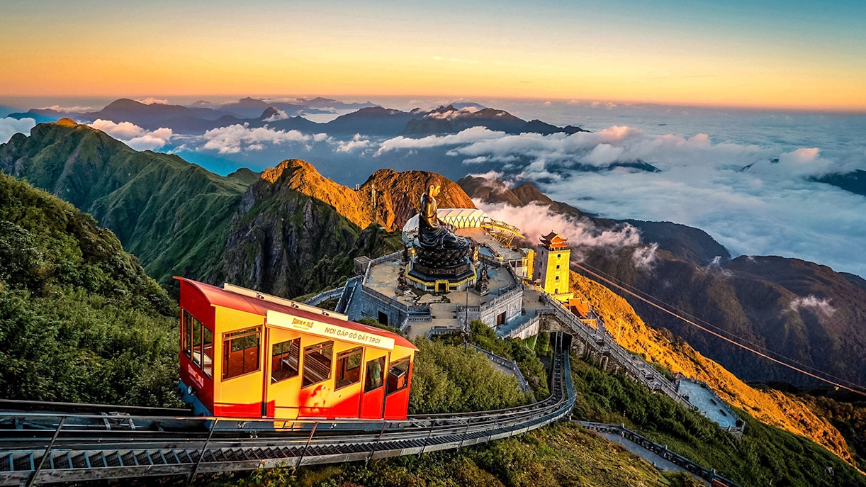Cable car ascending Fansipan Mountain with temple and statue at Sun World Fansipan Legend, Vietnam.