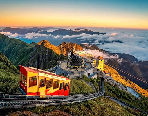 Cable car ascending Fansipan Mountain with temple and statue at Sun World Fansipan Legend, Vietnam.