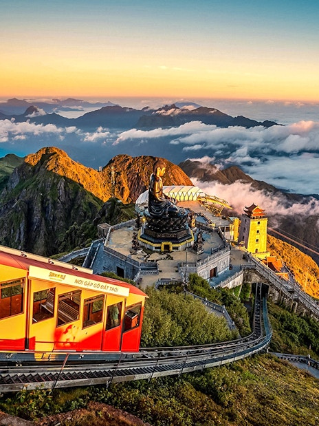 Cable car ascending Fansipan Mountain with temple and statue at Sun World Fansipan Legend, Vietnam.