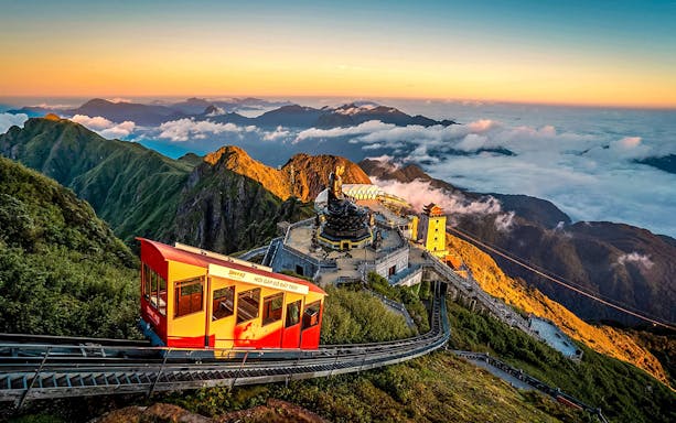 Cable car ascending Fansipan Mountain with temple and statue at Sun World Fansipan Legend, Vietnam.