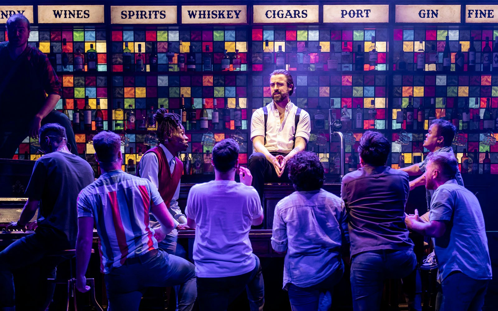 Men performing on stage at a bar setting in The Choir of Man show.