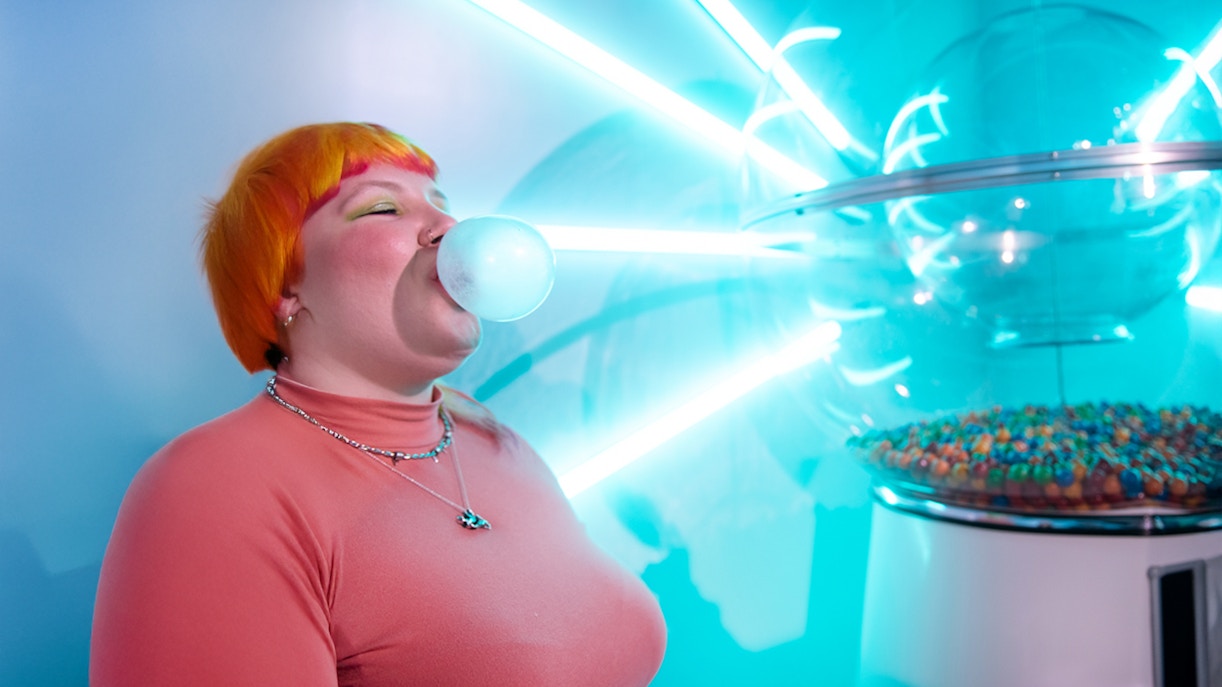Person blowing bubble gum near neon lights at Dopamine Land, Washington D.C.