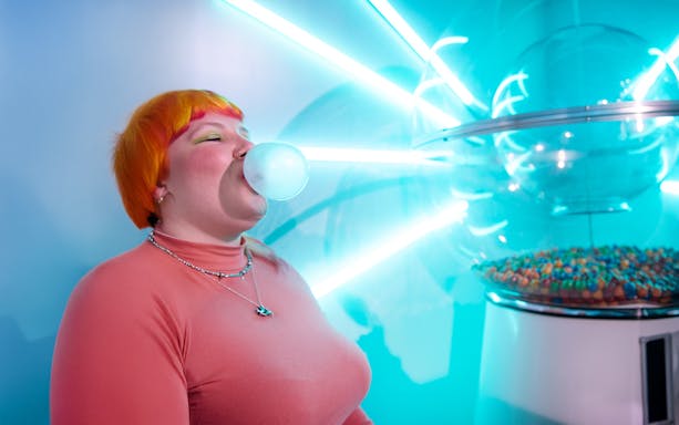 Person blowing bubble gum near neon lights at Dopamine Land, Washington D.C.