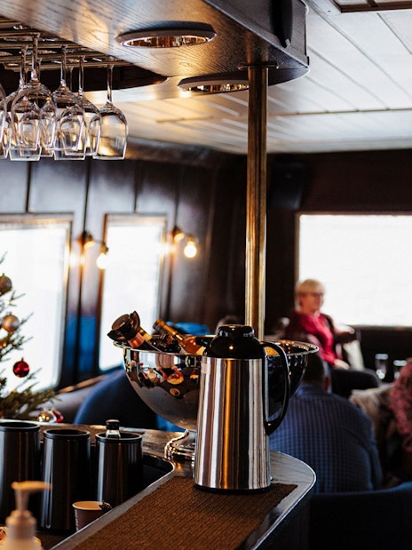 Bar area on a sightseeing cruise in Hjørundfjord, Norway, with a crew member preparing drinks.
