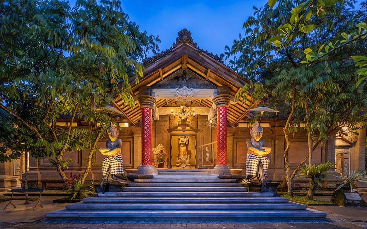 Arma Museum Resort entrance with statues and evening lighting in Bali.