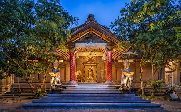 Arma Museum Resort entrance with statues and evening lighting in Bali.