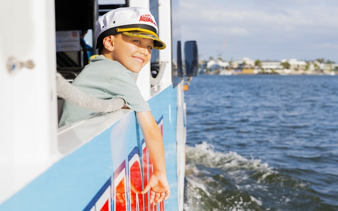 Child enjoying Aquaduck city tour and river cruise, leaning out of the boat.