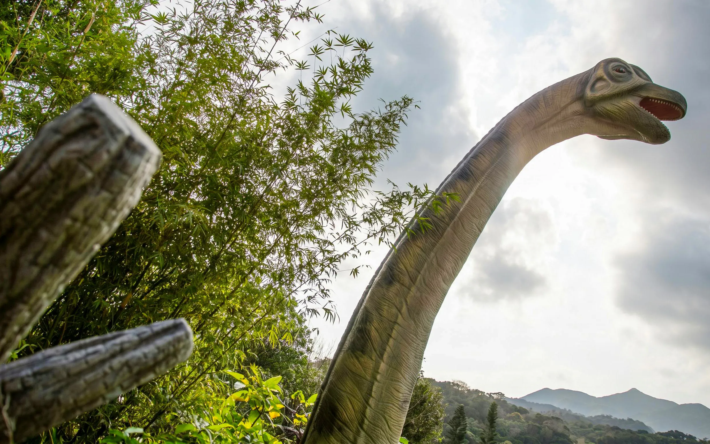 Dinosaur statue among trees at Okashigoten Nago Dino Park Yanbaru Subtropical Forest.