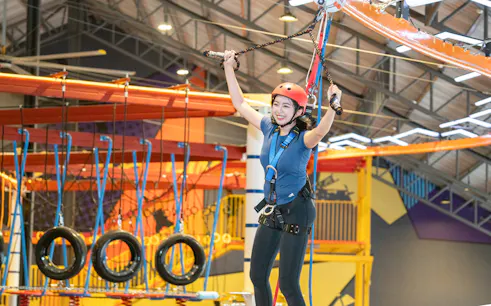 Person enjoying a ropes course at Monkey Canopy Resort's Indoor Extreme Park.