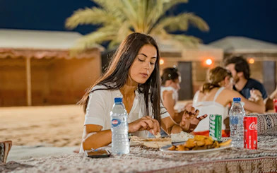 Woman dining at a desert safari overnight stay in Abu Dhabi.