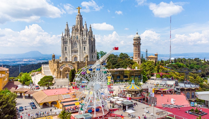 Tibidabo amusement park rides with panoramic view of Barcelona cityscape.