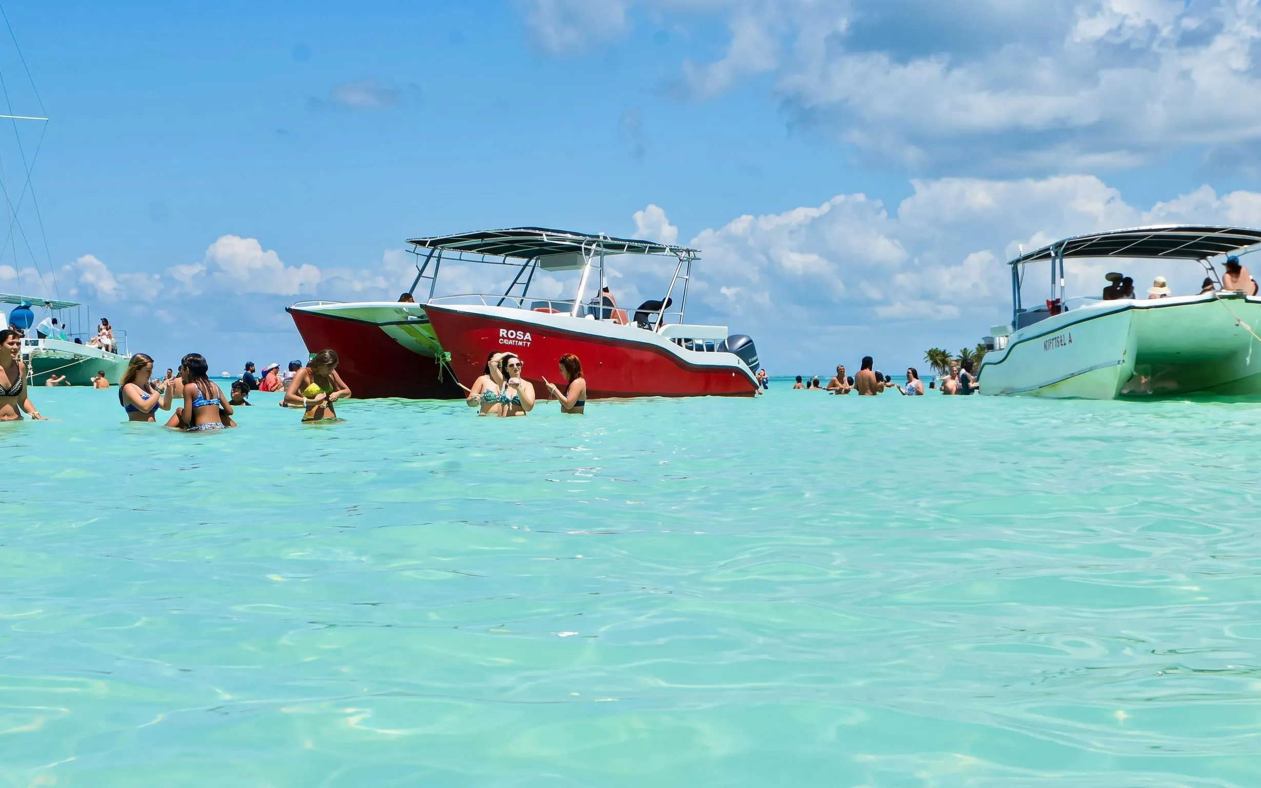 Catamaran anchored near Saona Island with people swimming in clear water, Punta Cana tour.