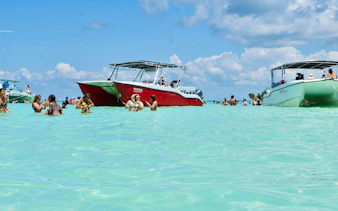Catamaran anchored near Saona Island with people swimming in clear water, Punta Cana tour.