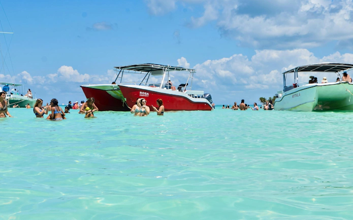 Catamaran anchored near Saona Island with people swimming in clear water, Punta Cana tour.