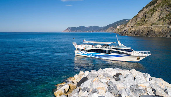 Boat near rocky coast on Riomaggiore, Monterosso, and Vernazza tour from La Spezia.