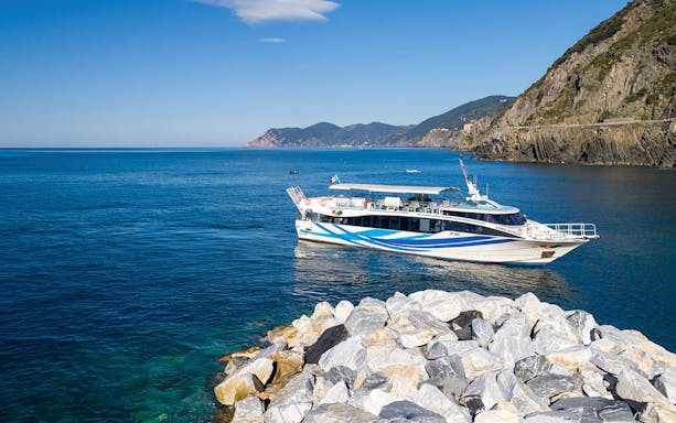 Boat near rocky coast on Riomaggiore, Monterosso, and Vernazza tour from La Spezia.