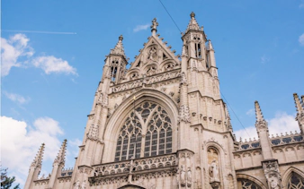 Gothic architecture of a historic church in Brussels under a blue sky.