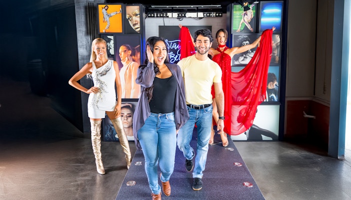 Walking on the runway at Madame Tussauds, New York with wax figures in the background.