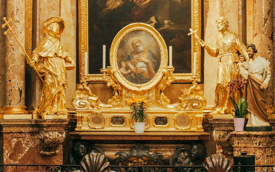 Golden altar with religious statues and painting inside St Anne's Church.