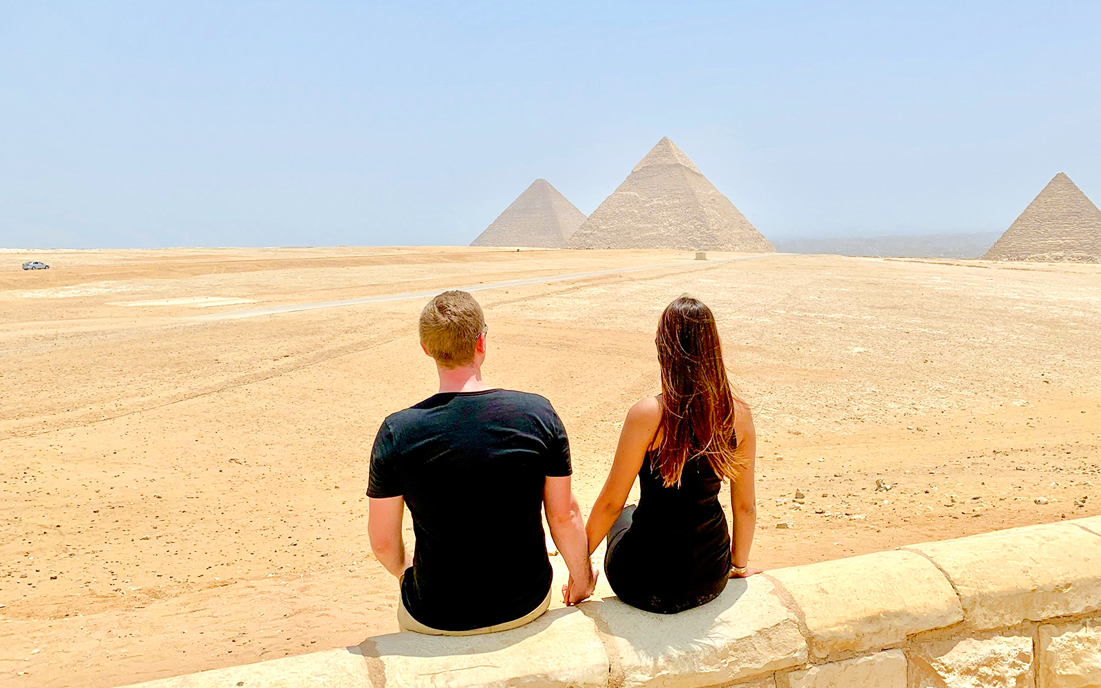 Couple sitting and viewing the Pyramids of Giza in Egypt.