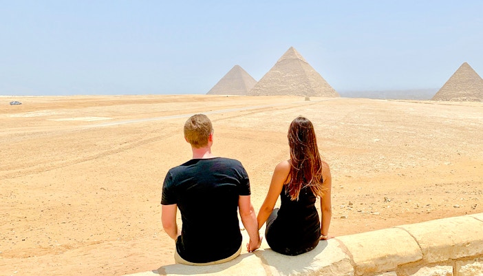 Couple sitting and viewing the Pyramids of Giza in Egypt.