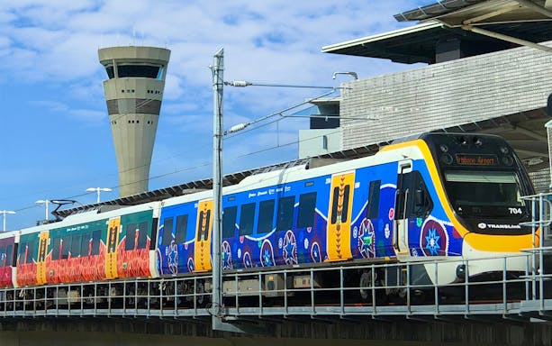 Train at Brisbane Airport station with control tower in background.