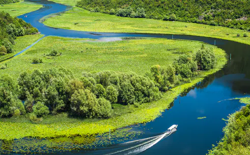 Crnojevica river bends and curves with boat in Montenegro.